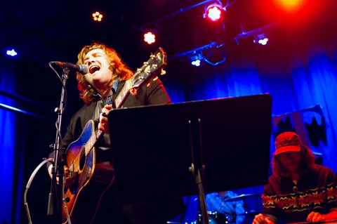 Singer with an electric guitar at the microphone at the 2025 Jason Molina MusiCares benefit.