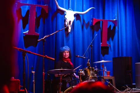 Drummer at the kit beneath the venue backdrop at the 2025 Jason Molina MusiCares benefit.