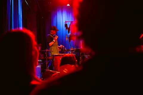 Seated musician on stage, seen over the audience at the 2025 Jason Molina MusiCares benefit.