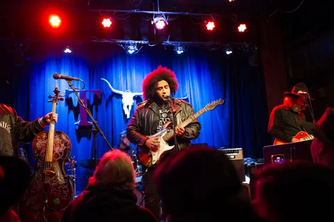 Electric guitarist and backing musicians facing the audience at the 2025 Jason Molina MusiCares benefit.