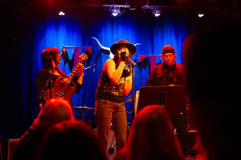Vocalist wearing a hat, with backing musicians at the 2025 Jason Molina MusiCares benefit.