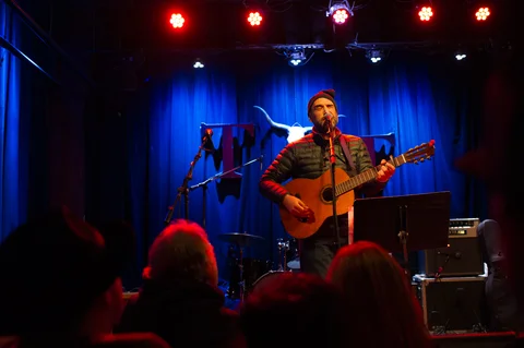 Singer playing electric guitar at the center microphone at the 2025 Jason Molina MusiCares benefit.