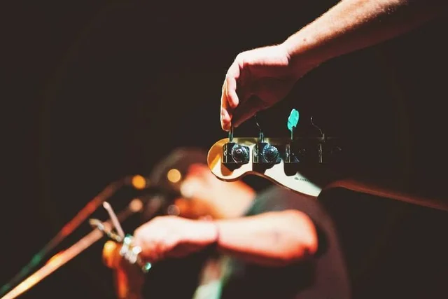 Hand turning a tuning peg on a guitar. The Trouble Starts, East release show, August 16, 2013.