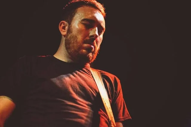 Portrait of a band member under warm stage lighting. The Trouble Starts, East release show, August 16, 2013.