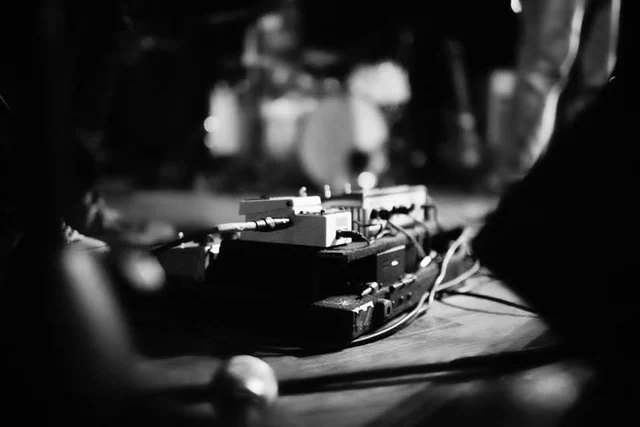 Black-and-white close-up of effects pedals on stage. The Trouble Starts, East release show, August 16, 2013.